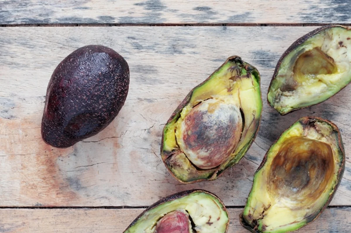 overripe avocado on wooden table close up