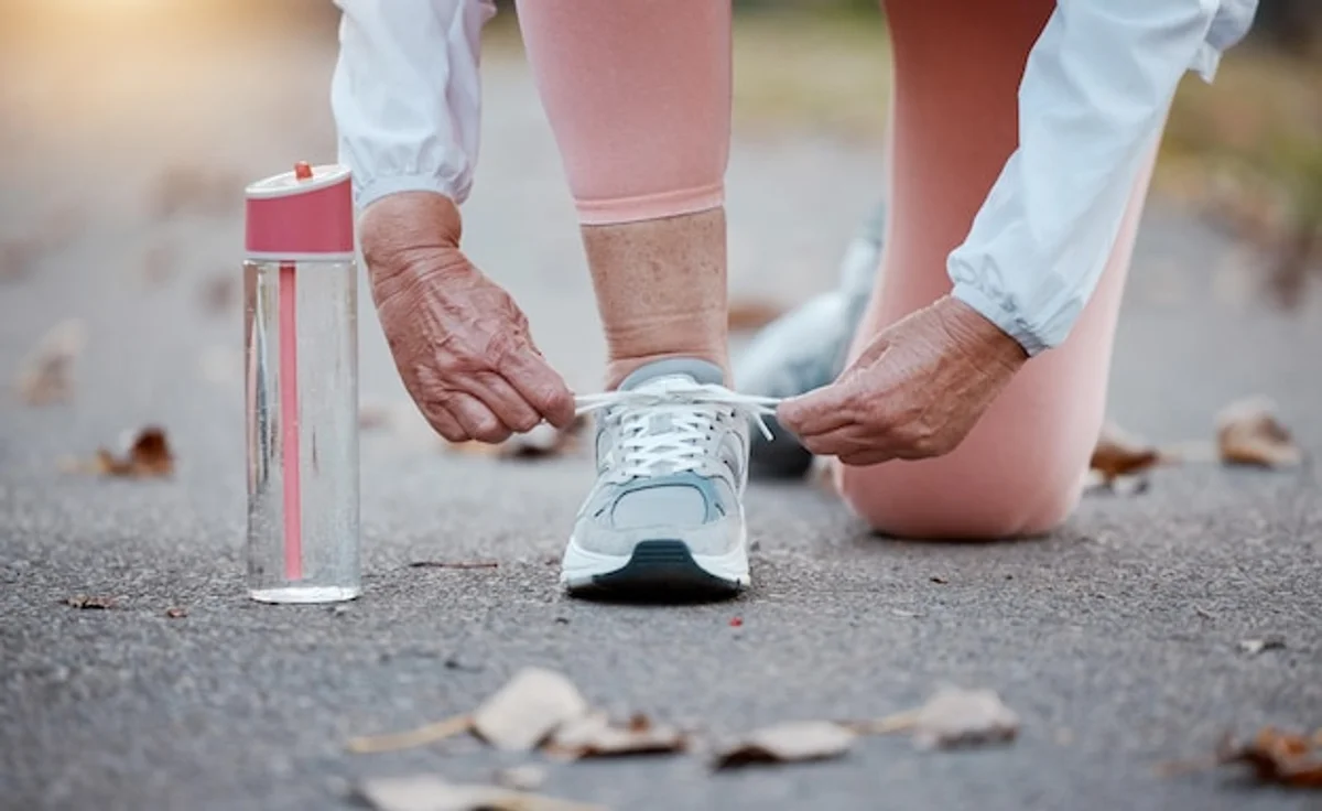 old athlete tying running shoes preparing for marathon sunrise
