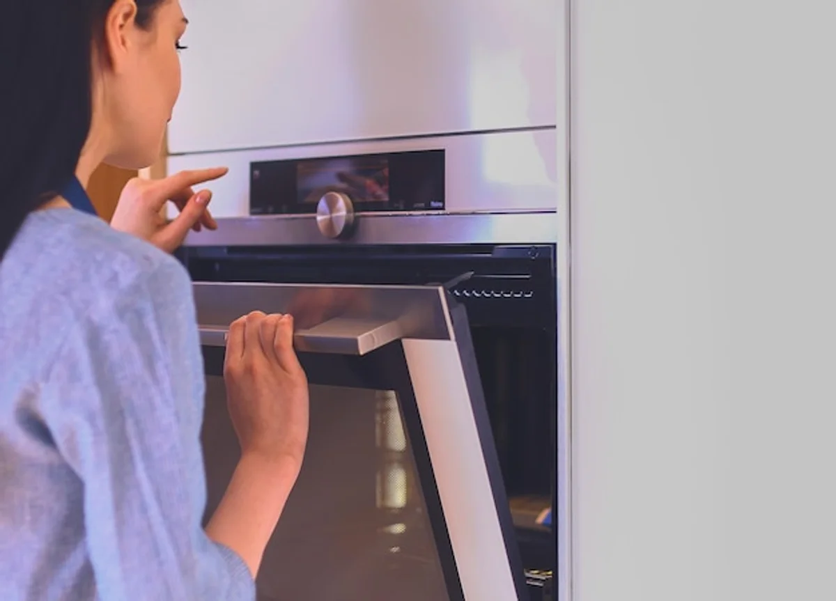 closeup hand opening oven door with cake inside, home baking