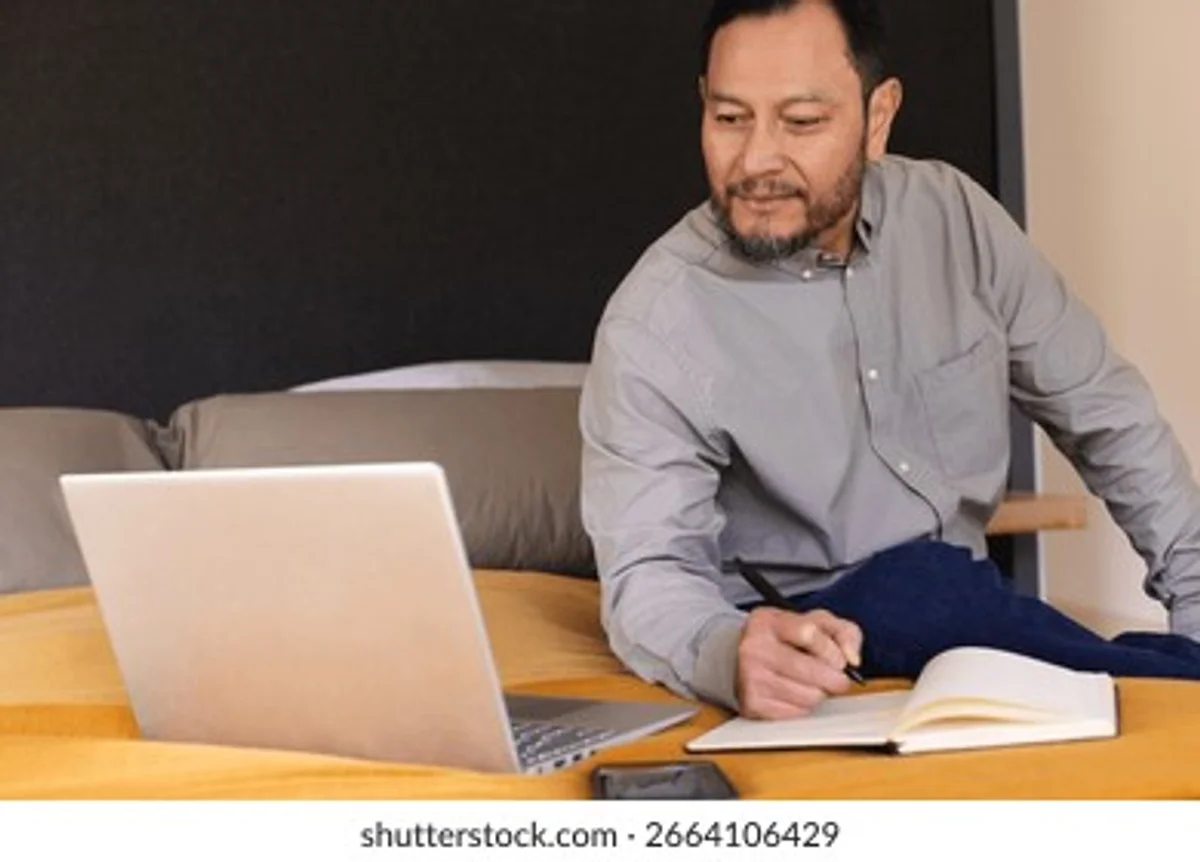 Person konzentriert arbeitet Notizbuch Laptop Sonnenlicht Fenster minimalistisch