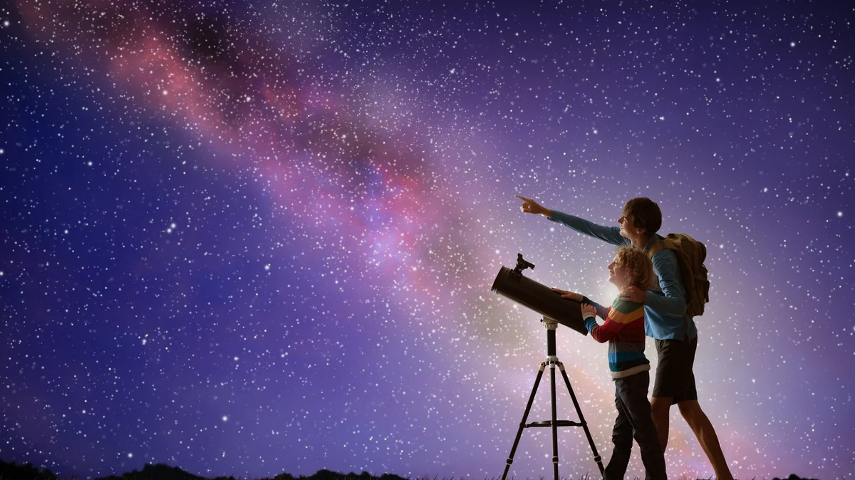 People stargazing in Germany open field night sky with telescopes