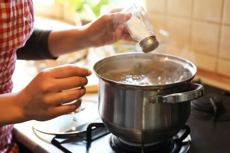 salt thrown into boiling water kitchen closeup