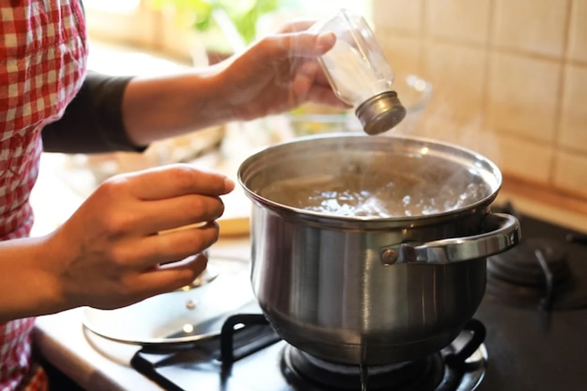 salt thrown into boiling water kitchen closeup